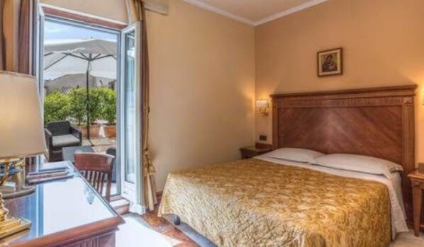 Habitación de hotel con cama, escritorio y silla. Ventana con vista al exterior.