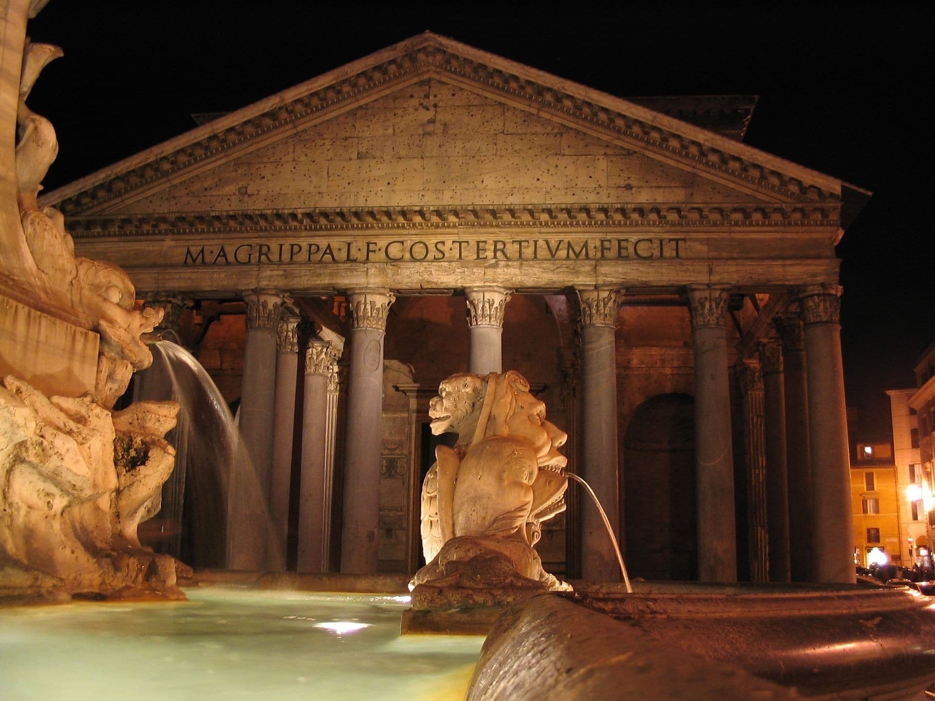 A classical building with columns and a statue in front.