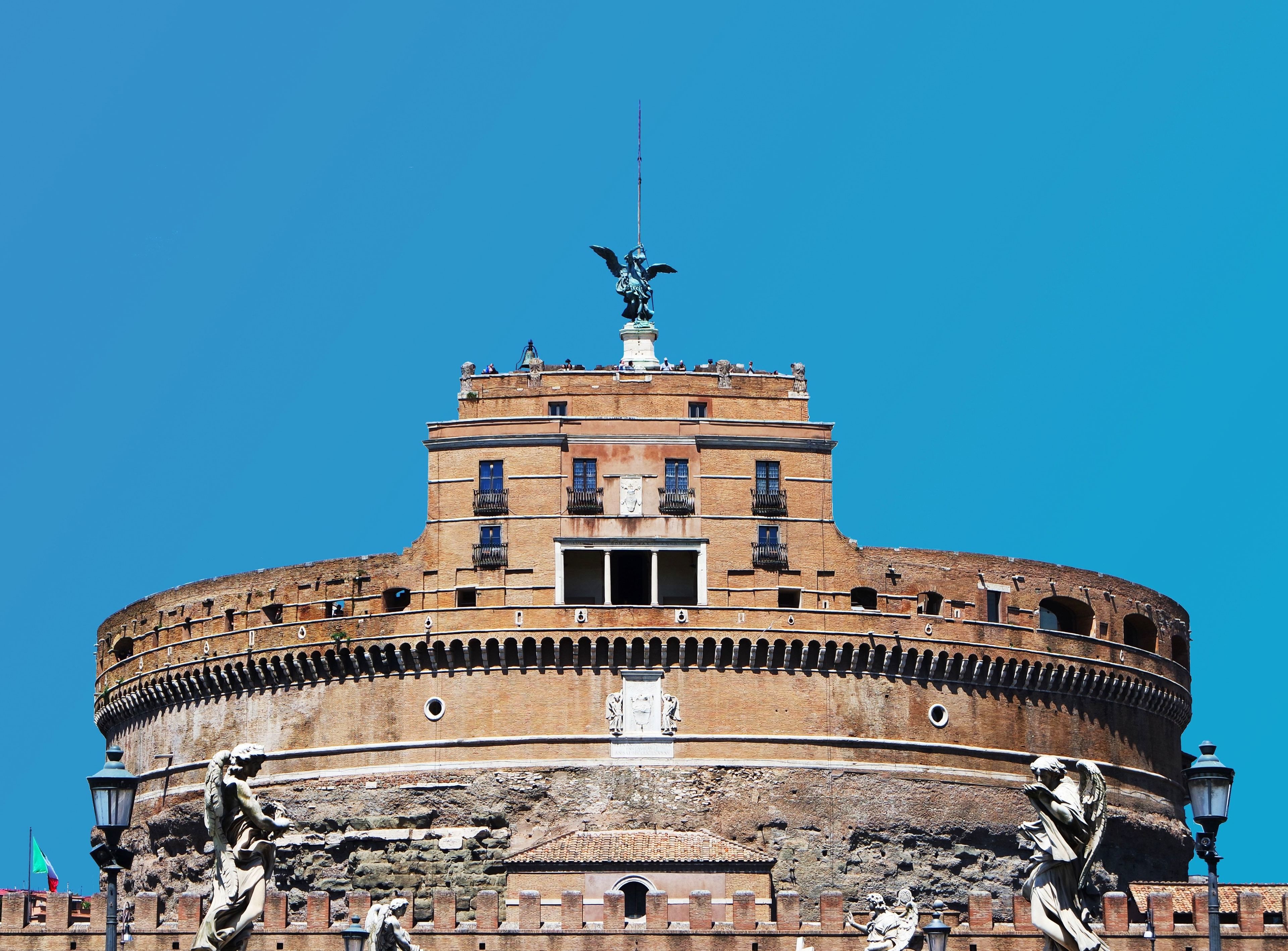 A historic building with a circular structure, a central open area, and statues at the base.