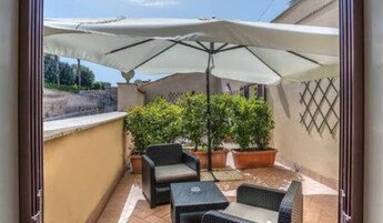 A patio area with outdoor furniture, a large umbrella, and potted plants.