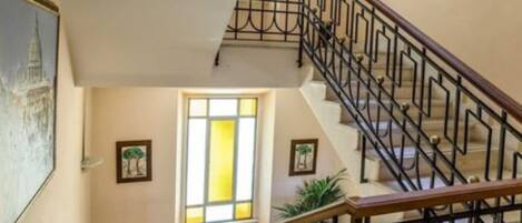 Un escalier avec une main courante en bois et des rampes en métal noir, menant à l’étage supérieur.