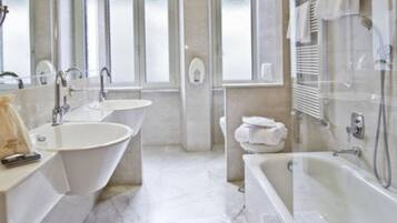 Een badkamer met twee wastafels, een badkuip en een douche.