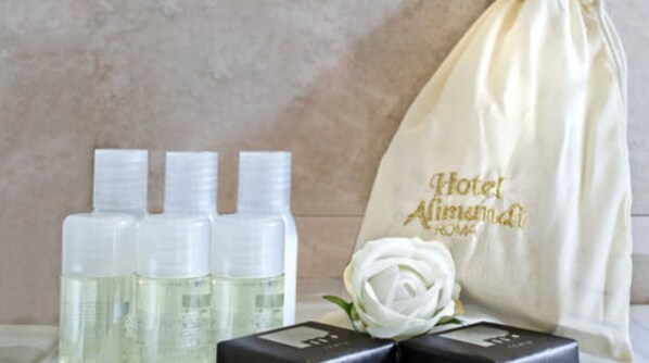 A set of toiletries, a white rose, and a hotel bag with "Hotel Alimandina Roma" embroidered on it.