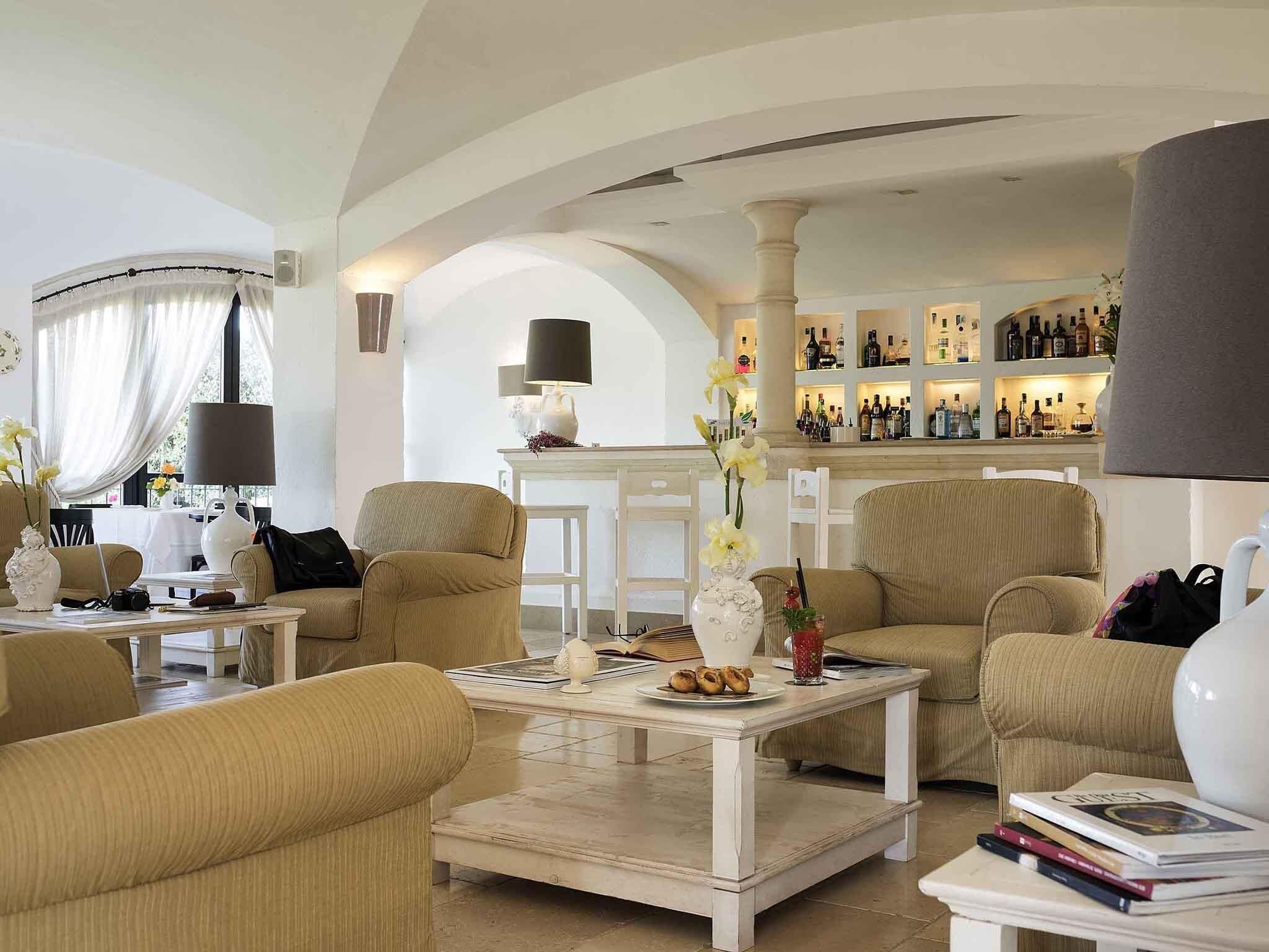 Amplia sala de estar con techos altos, una zona de bar con estantes llenos de botellas y un mobiliario cómodo.