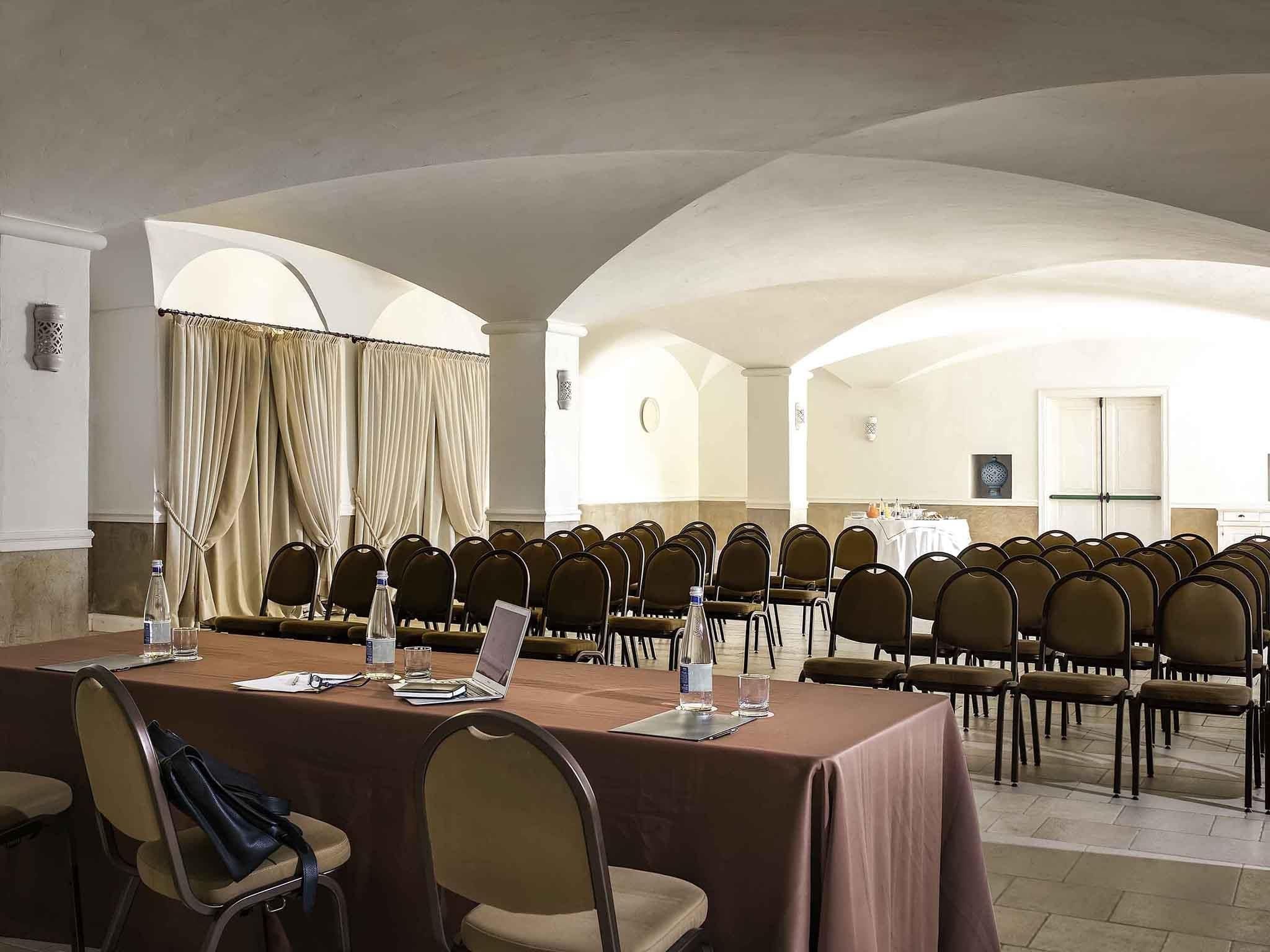 Une salle de conférence avec une longue table, des chaises et un ordinateur portable.