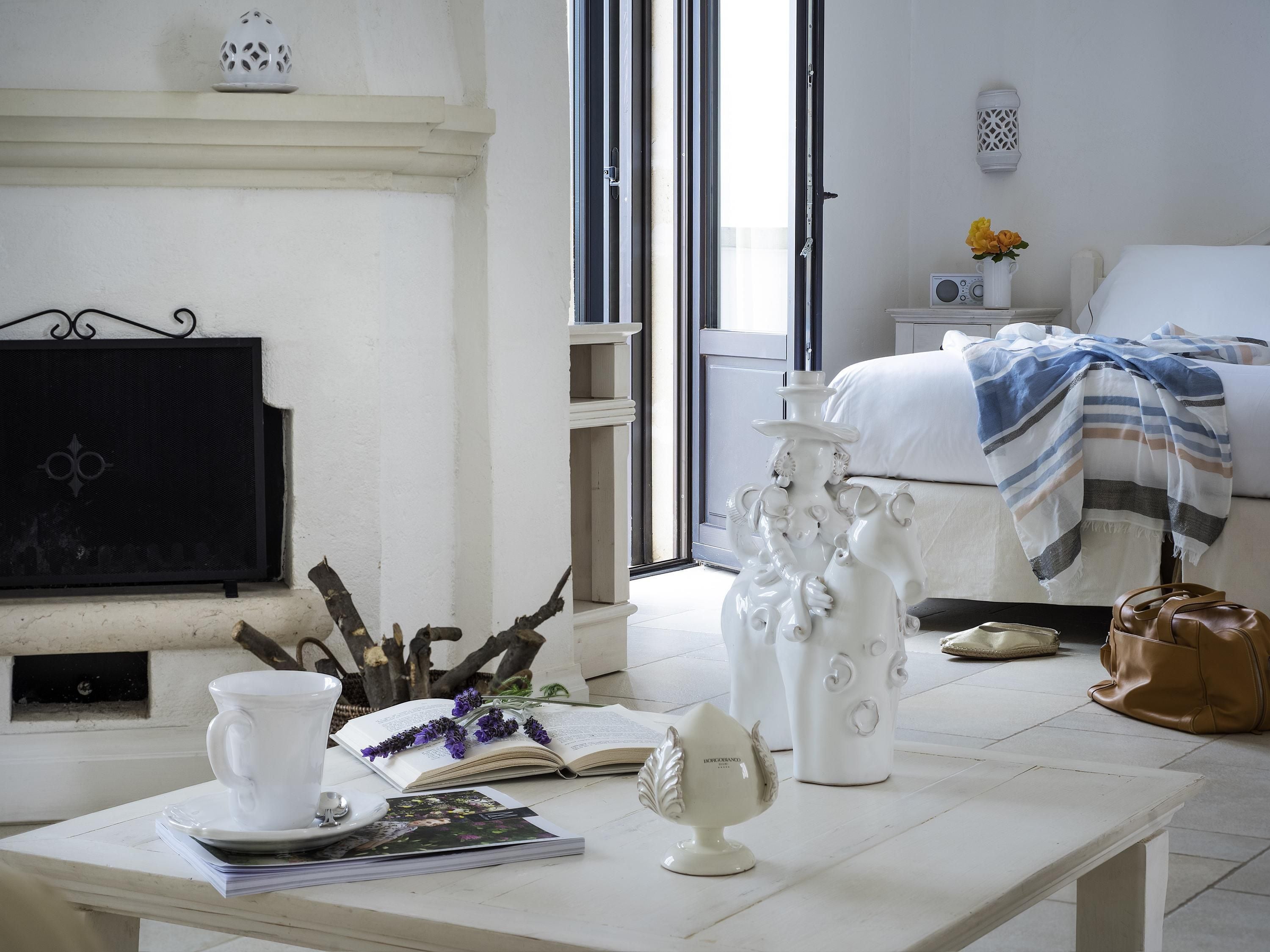Una habitación con una mesa blanca, un jarrón blanco, un libro y un adorno decorativo.