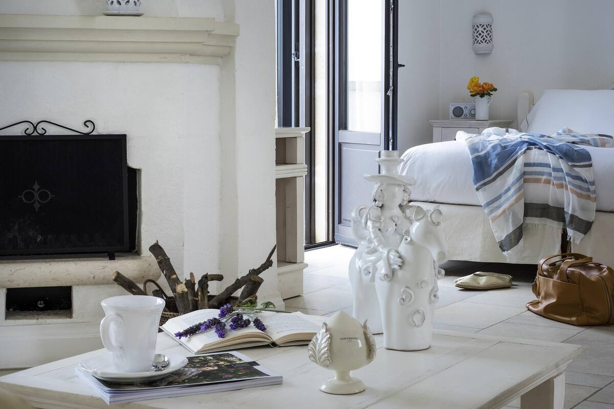 A room with a white table, a white vase, a book, and a decorative item.