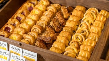 A wooden display case filled with various pastries, including croissants and Danish pastries, with labels in a foreign language.