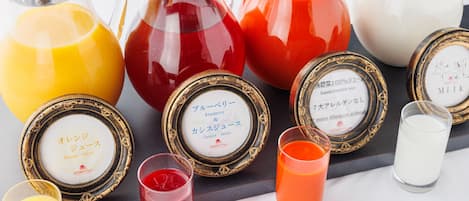 A variety of beverages in different containers, including a pitcher, a carafe, and glasses, each with a label indicating the type of drink.