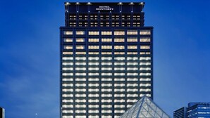 Moderni hotelli, jossa on lasijulkisivu ja sen edessä erottuva pyramidinmuotoinen rakennelma.