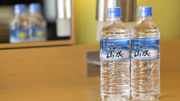 Two mineral water bottles on a wooden surface with a mirror reflecting the bottles and a metallic object in the background.