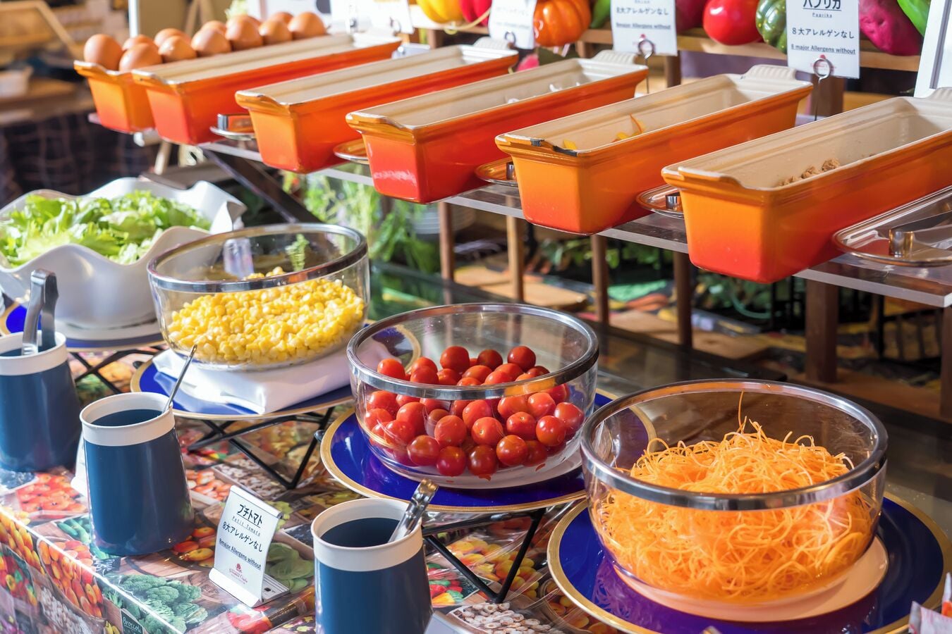 Un bufé con diversas opciones de comida, como maíz, tomates cherry y queso rallado.