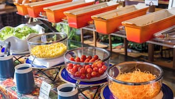 Un bufé con diversas opciones de comida, como maíz, tomates cherry y queso rallado.