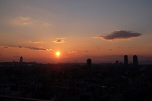 Eine Stadtansicht im Abendrot, die Sonne steht tief am Horizont.