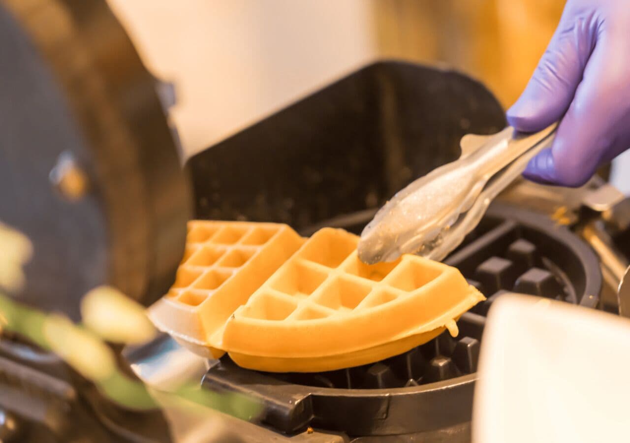 A waffle being cooked on a waffle iron.