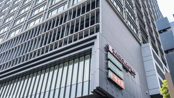 A modern high-rise building with a prominent sign for the "Hotel New York" and a visible entrance.