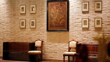 A room with a stone wall, framed artwork, and wooden benches.