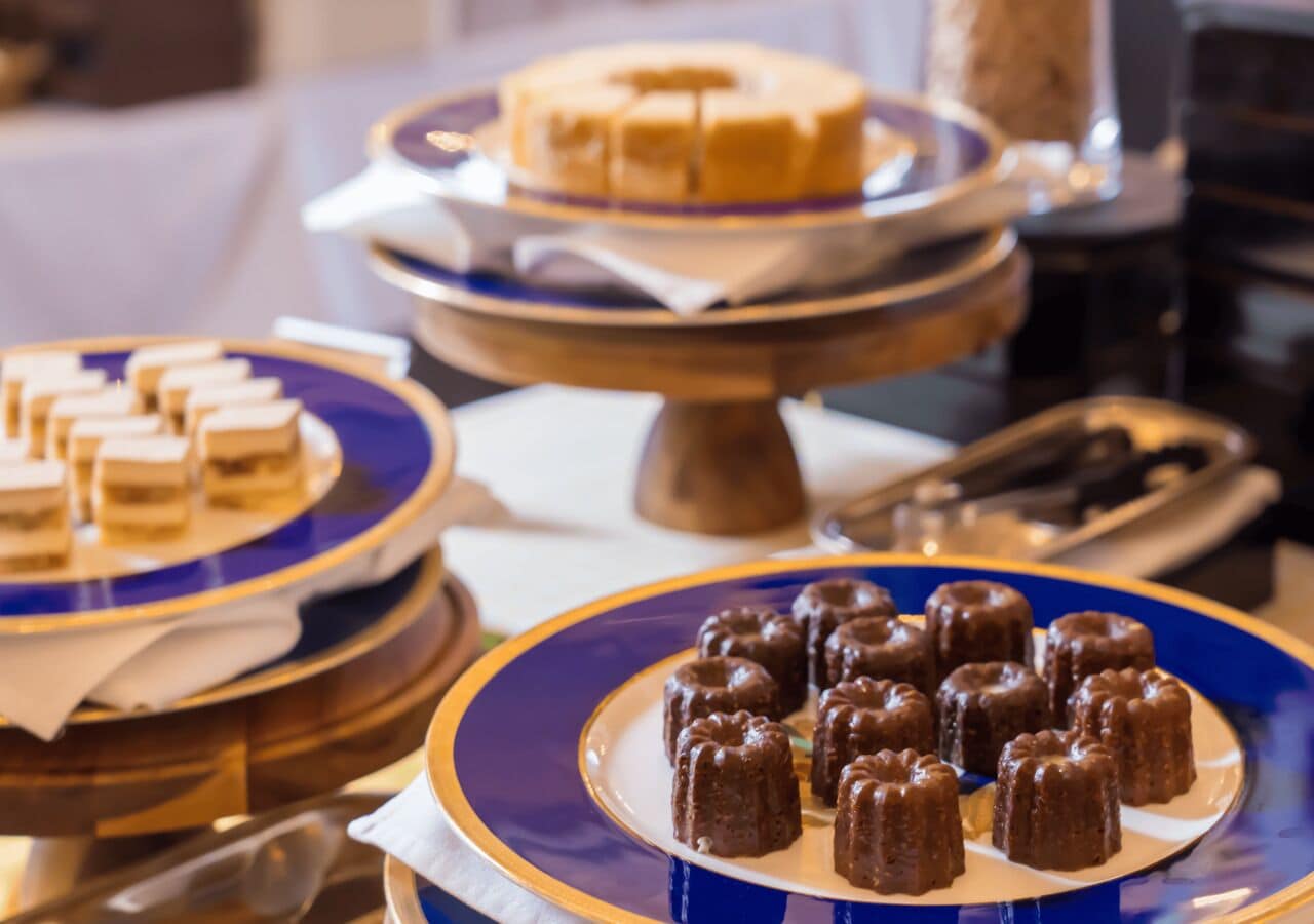 A buffet with various desserts on plates and stands.