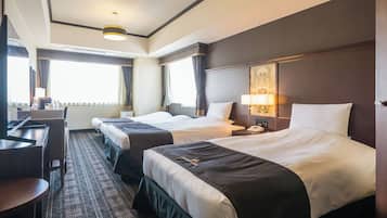 Habitación de hotel con dos camas, un escritorio y un ventanal grande.
