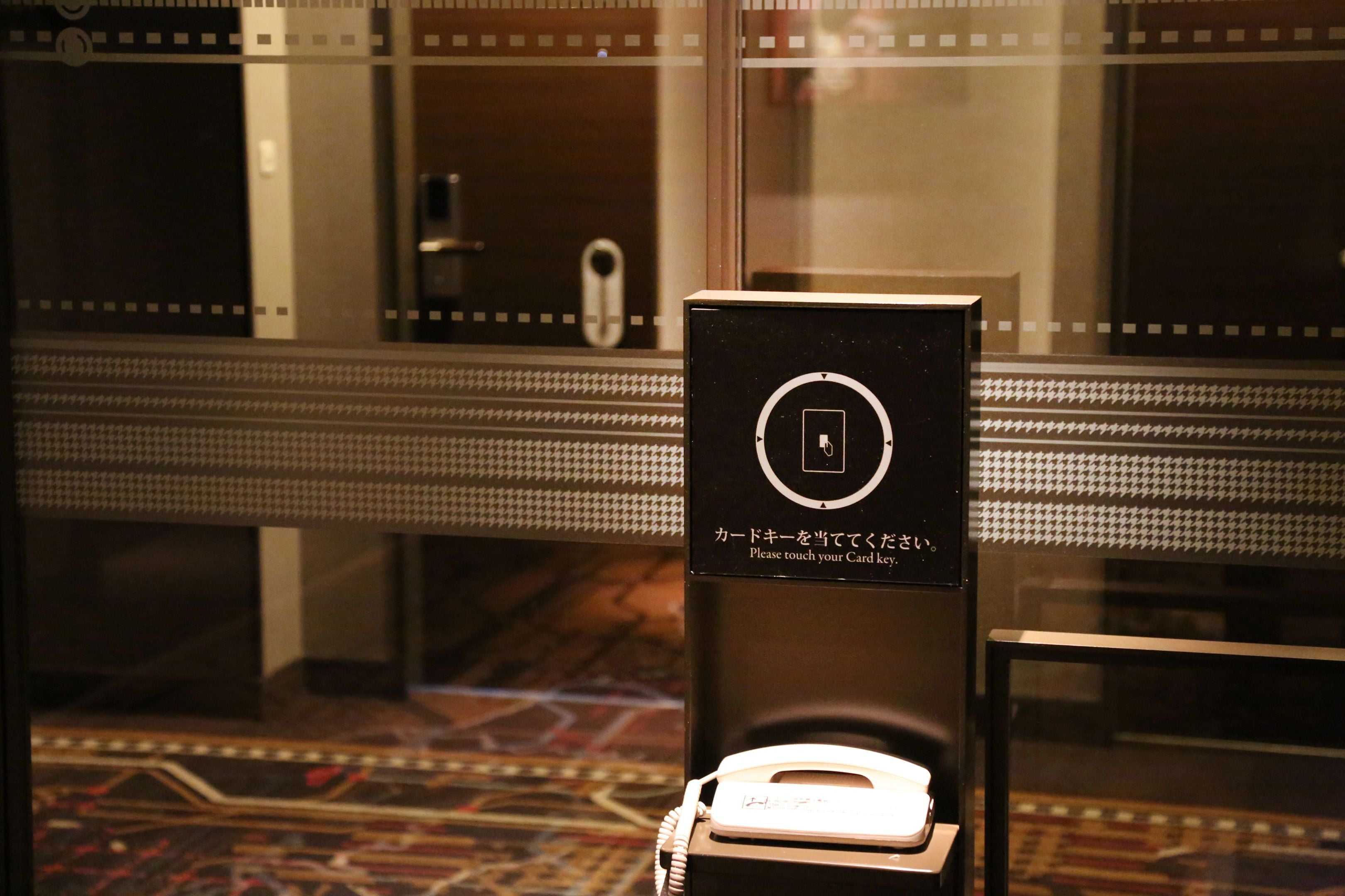 A hotel reception area with a card reader and a glass door.