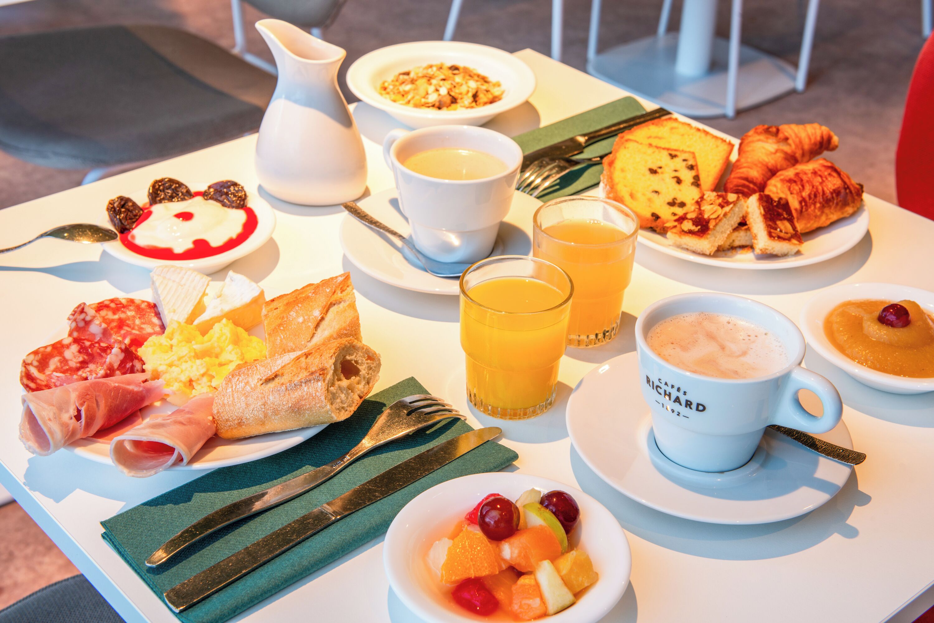 A breakfast table with various food items and beverages.