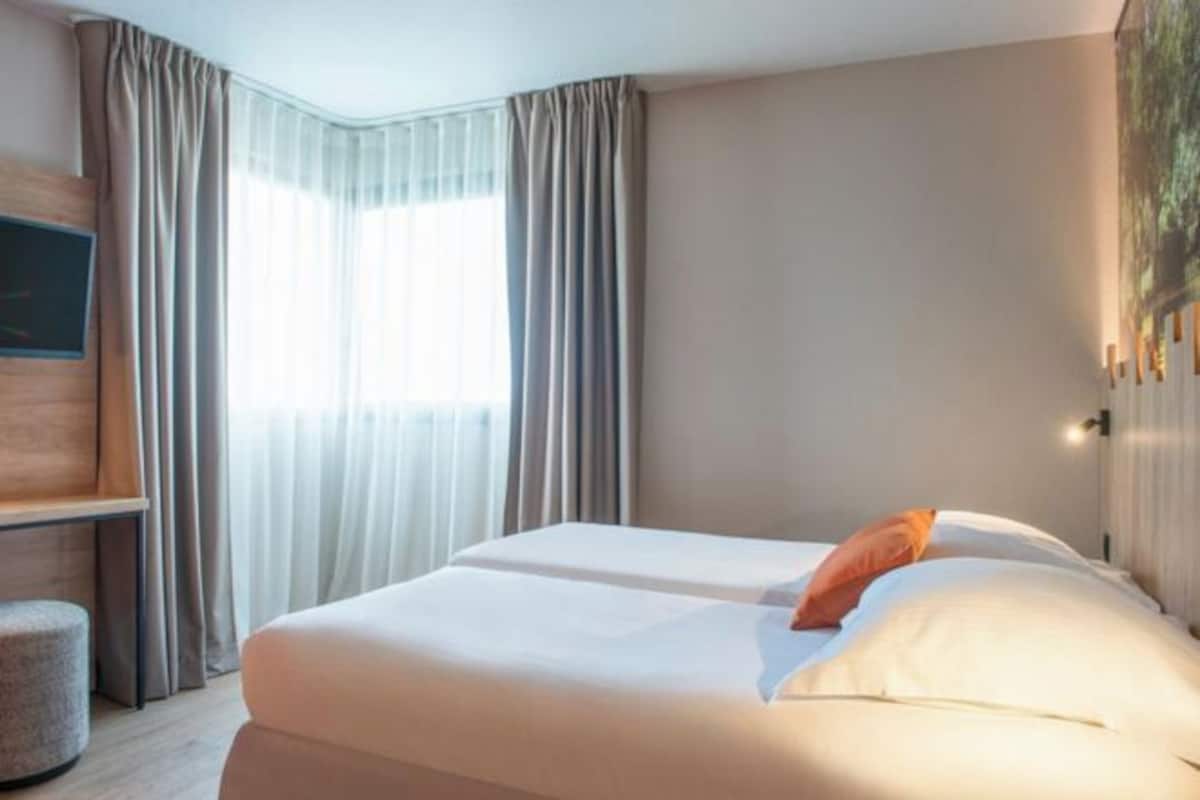 Ett hotellrum med en säng, ett skrivbord och en stol.