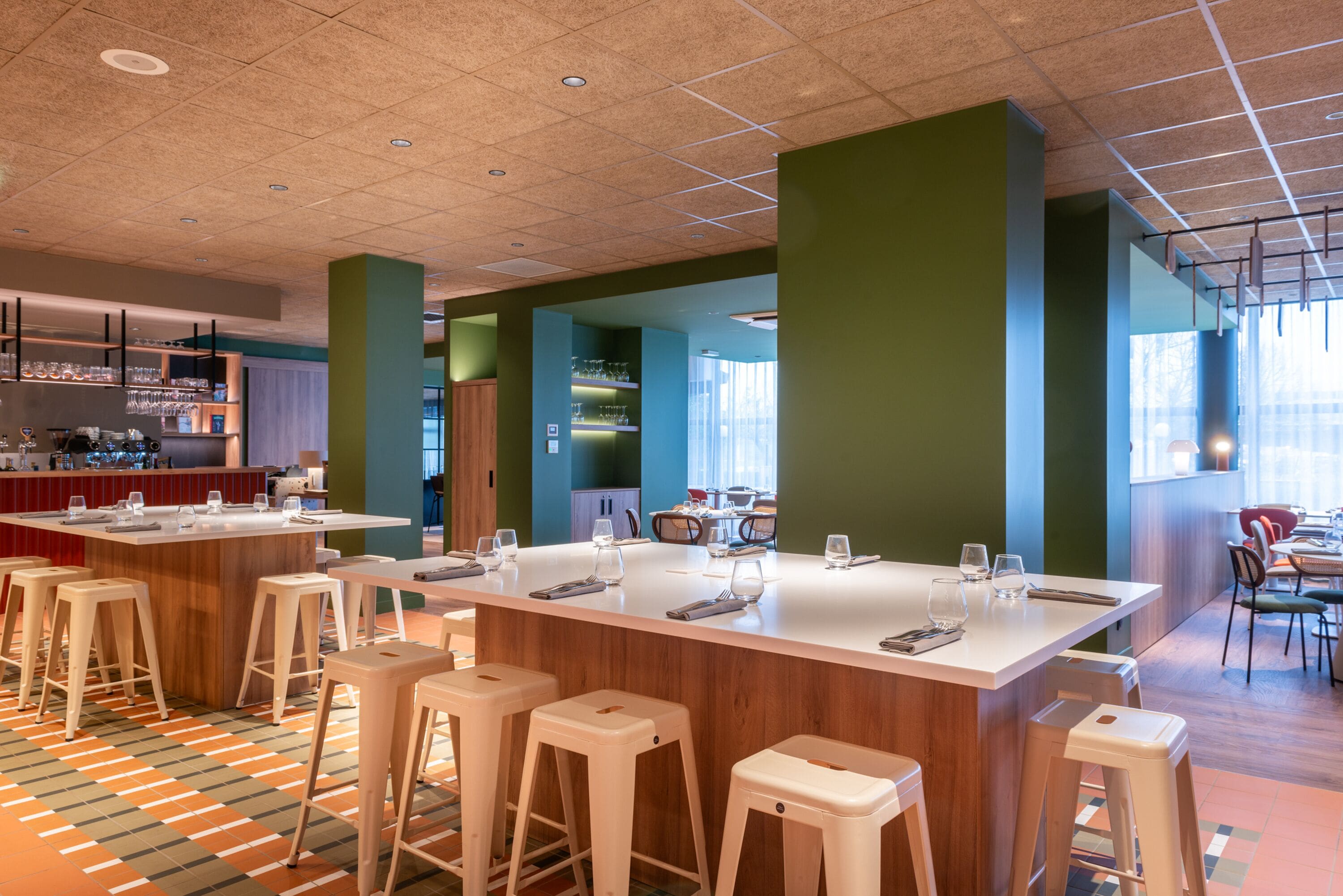 A modern bar area with stools, a bar counter, and shelves with glasses and bottles.