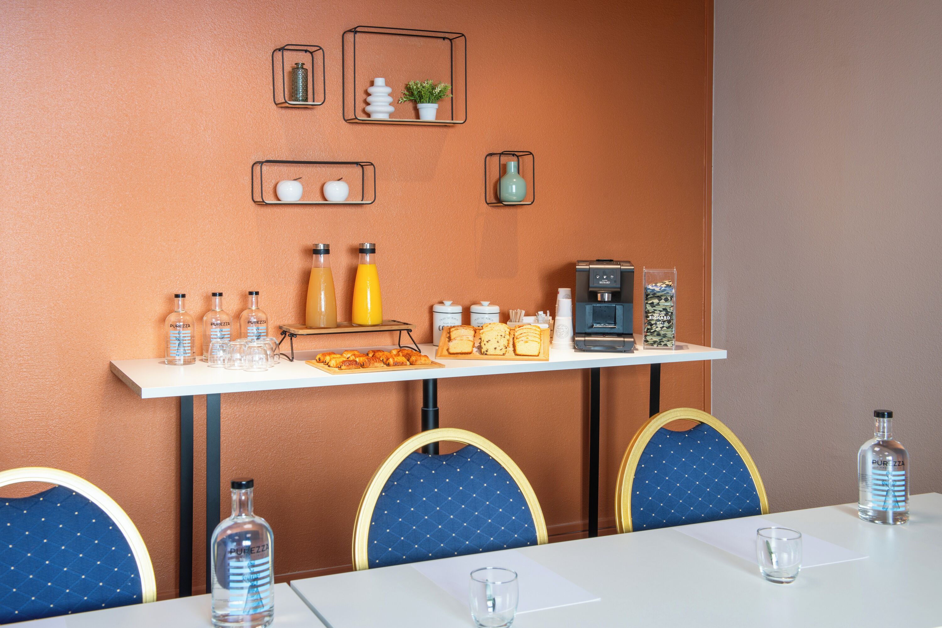 Una barra de desayuno con bebidas, pasteles y una máquina de café.
