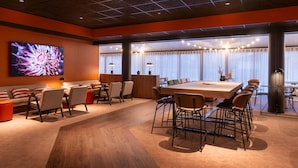 A modern conference room with a large table, chairs, and a large screen.