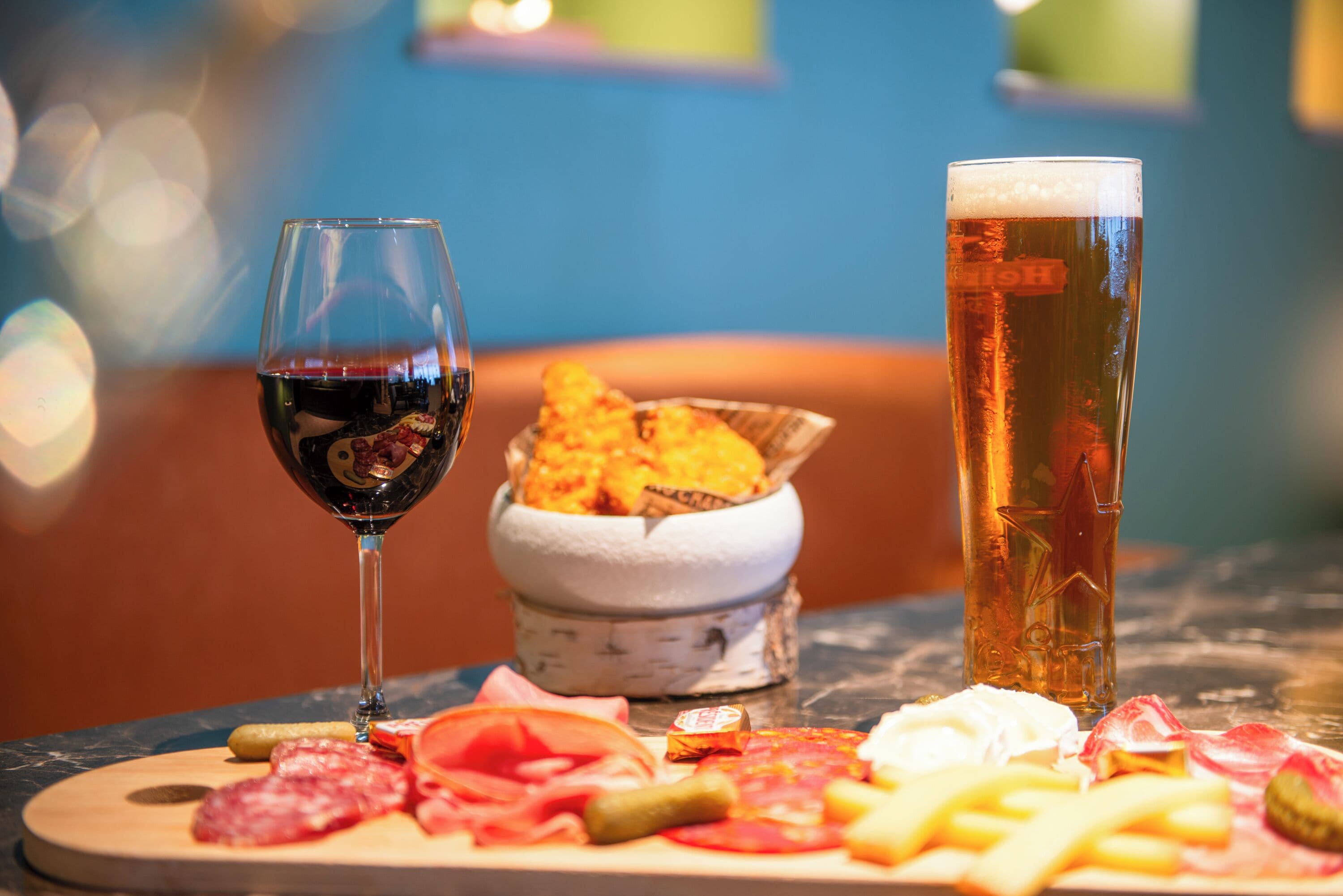A table with a variety of meats, cheese, and a glass of red wine.