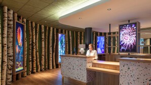 A reception area with birch tree decor, wooden reception desk, and large digital screens displaying floral patterns.