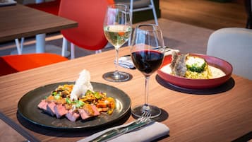Une table à manger avec deux assiettes de nourriture, deux verres à vin et une fourchette.