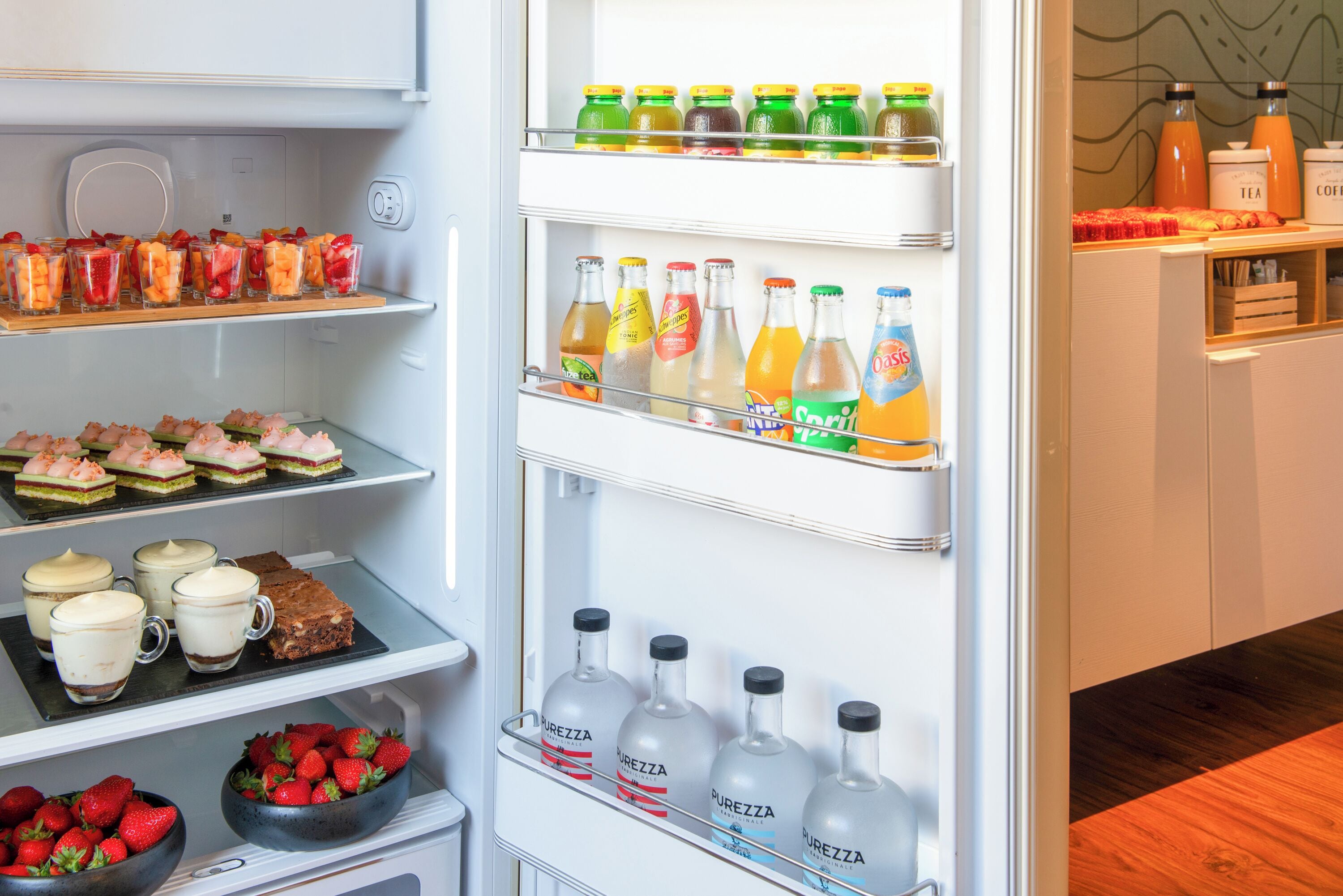 A refrigerator stocked with beverages, desserts, and coffee.