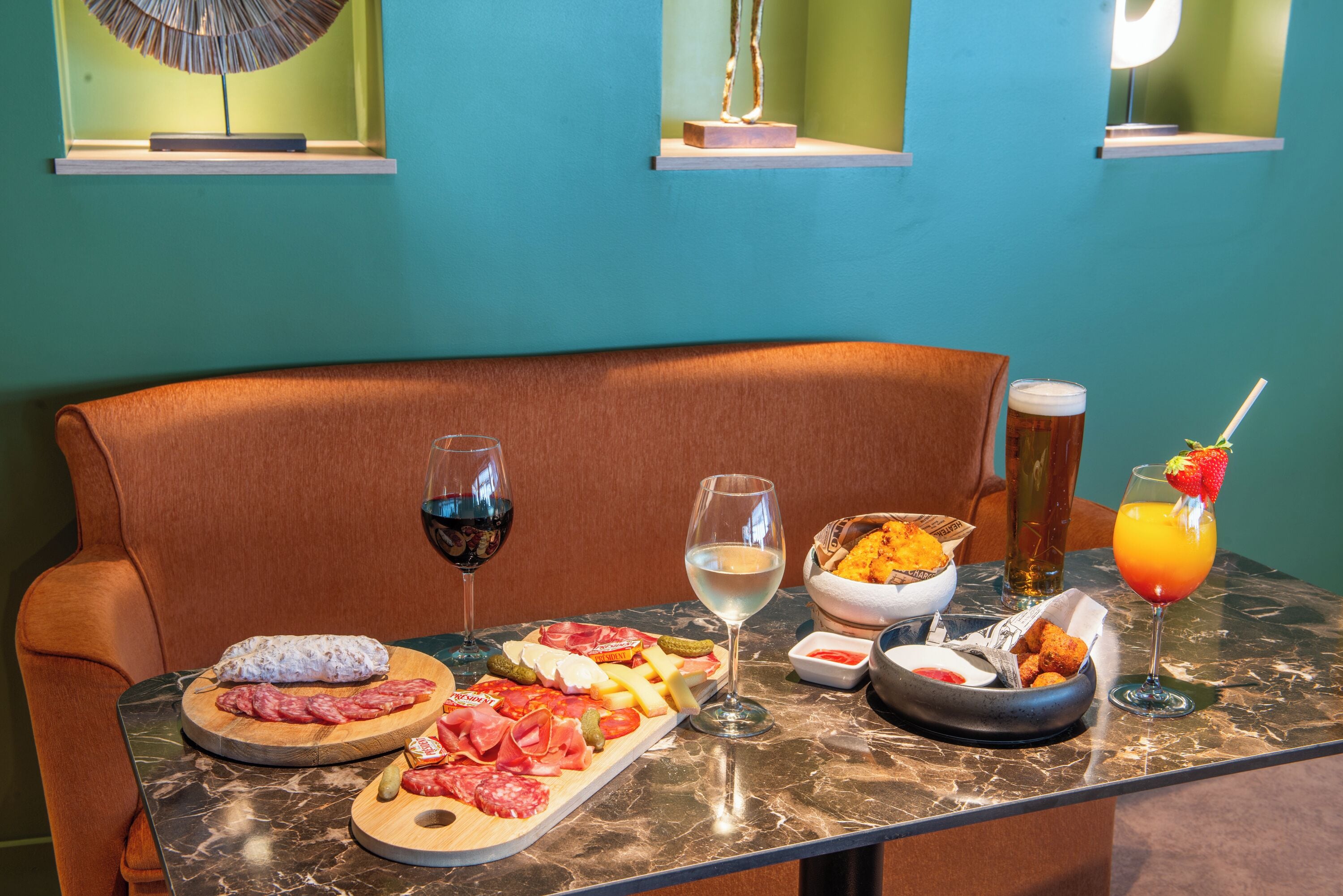 A table set with a charcuterie board, wine glasses, and a cocktail.