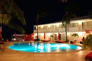 A swimming pool surrounded by palm trees and a building with balconies. - Decameron Los Delfines All Inclusive (San Andrés)