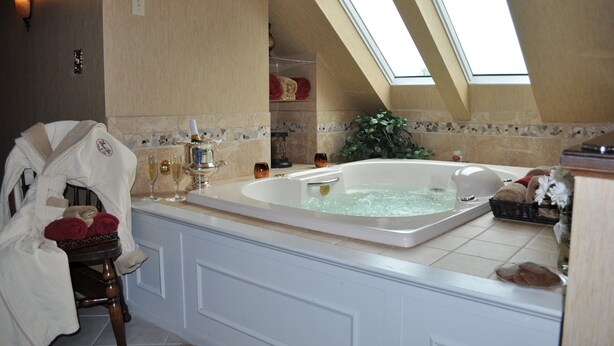 A bathroom with a large bathtub, a skylight, and a towel rack with towels. - The Inn & Spa at Intercourse Village (Gordonville)