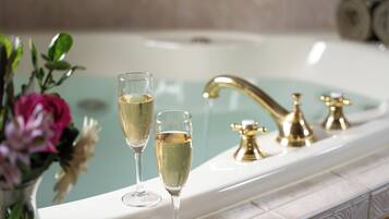 Une baignoire avec deux coupes à champagne et un robinet doré.