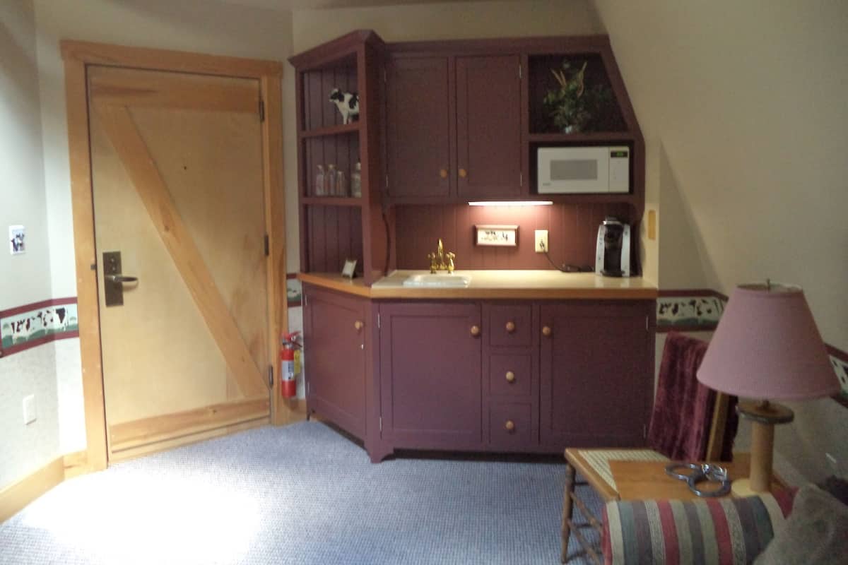 Una piccola cucina con una porta di legno, un forno a microonde e un lavandino.