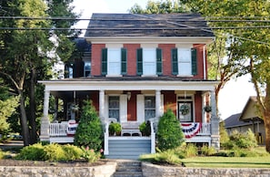A two-story house with a porch, a front yard, and a mailbox.