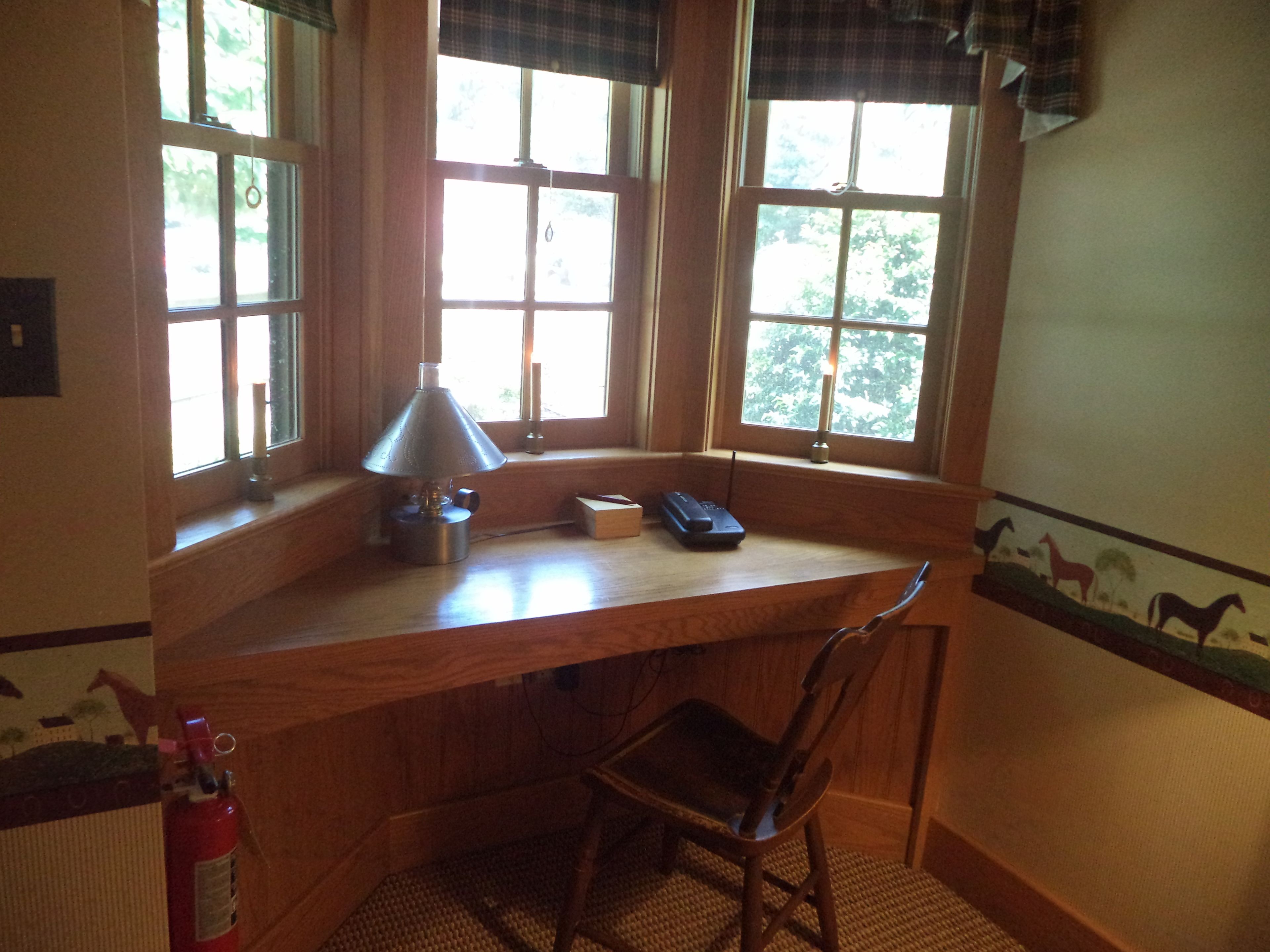 Un bureau d’angle avec une lampe, une chaise et une fenêtre avec des rideaux.