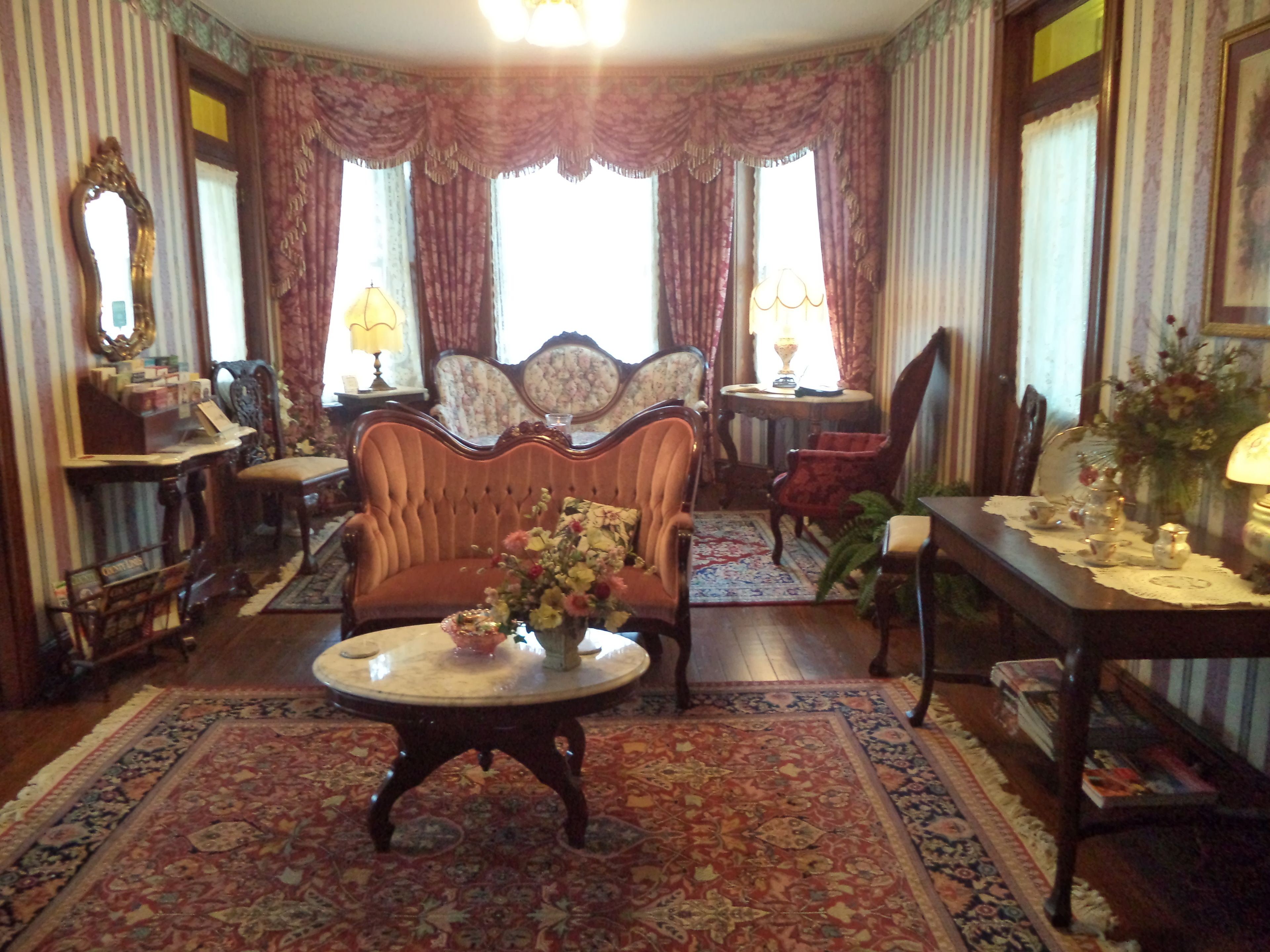 A traditional room with a sofa, armchairs, a round table, and a patterned rug.