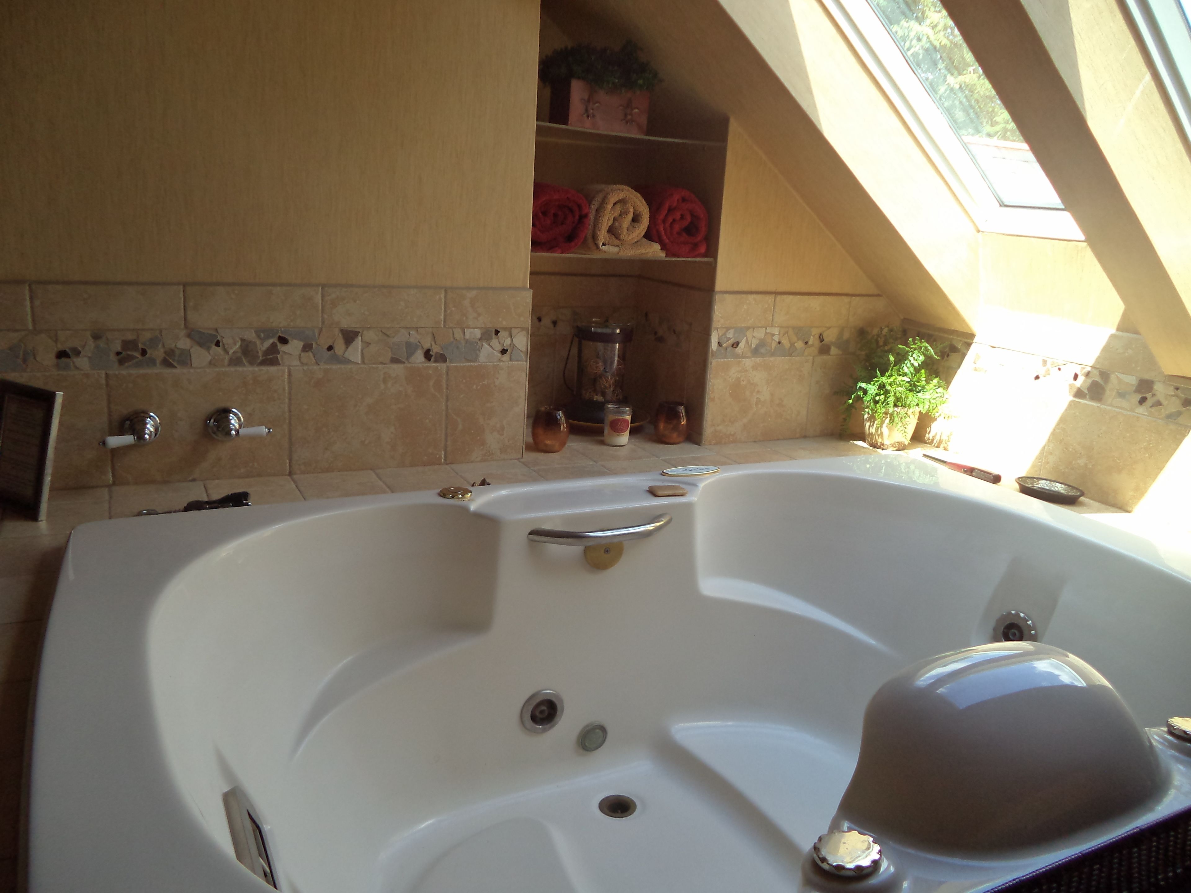 A bathroom with a large bathtub, a shower, and a window providing natural light.