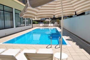 Una piscina al aire libre, sillones reclinables de piscina