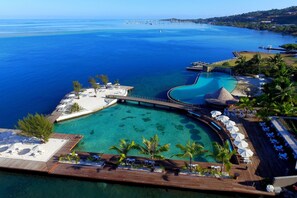 A resort with a large pool, a wooden deck, and a view of the sea. - Te Moana Tahiti Resort (Punaauia)