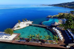 Un complexe hôtelier doté d’une grande piscine, d’une terrasse en bois et offrant une vue sur la mer.