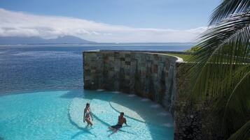 Una piscina al aire libre, sombrillas, sillones reclinables de piscina