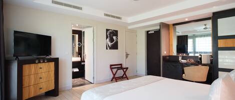 A modern hotel room with a large bed, a TV, a wooden cabinet, and a small seating area.