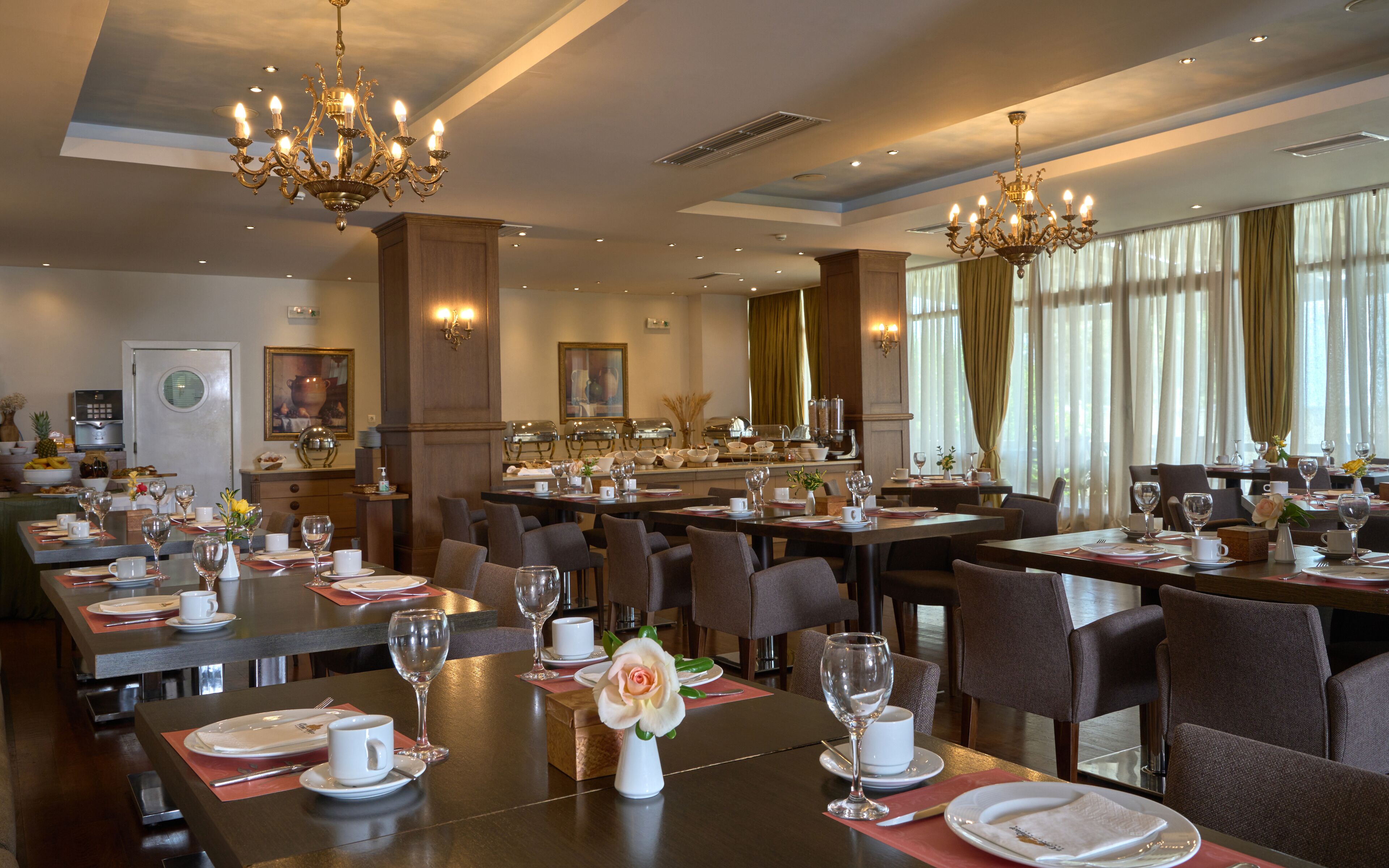 En hotellrestaurang med flera bord dukade för middag, utrustade med vinglas och tallrikar.