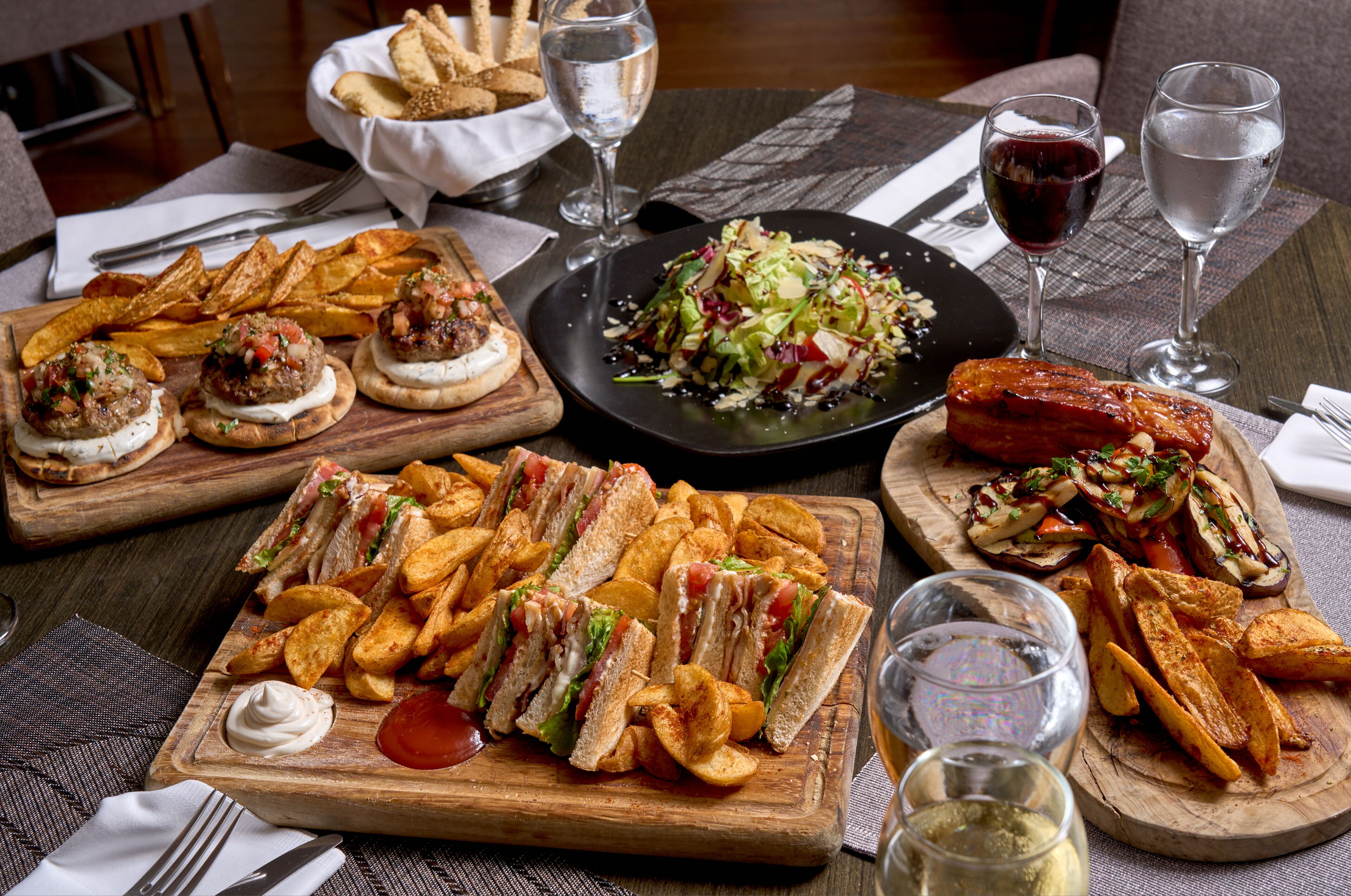 Una mesa con diferentes alimentos, incluyendo sándwiches, papas fritas y una ensalada.