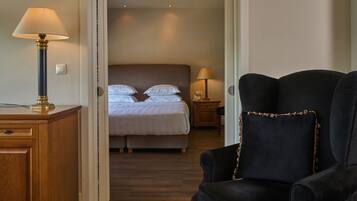 A hotel room with a bed, a chair, a desk, and two bedside lamps.